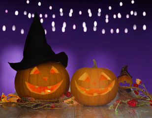 holidays, halloween and decoration concept - close up of carved pumpkins on table over ultra violet background