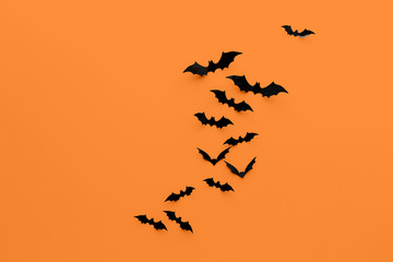 halloween decorations concept - many black paper bats on orange background