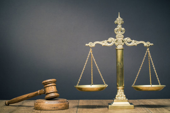 Vintage law scales and wooden gavel on the desk front dark background. Symbols of justice. Retro old style filtered photo
