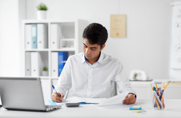 business and people concept - businessman with papers and laptop computer working at office