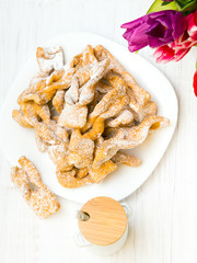 Faworki - Traditional Polish cookies served at Fat Thursday.  Cookies and tulip bouquet on white wooden background