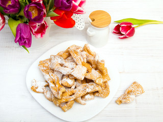 Faworki - Traditional Polish cookies served at Fat Thursday.  Cookies and tulip bouquet on white wooden background