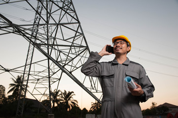 Asian engineer is controlling the construction on twilight bacground,Engineer using a mobile phone to contact the job
