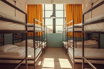 Light in window of hostel bedroom with clean white bunk beds for students and tourists
