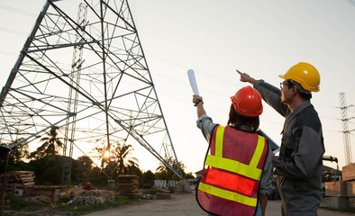 Engineers is pointing the job,Engineers  is setting goal,Engineers is controlling the construction on twilight background,Asian engineers