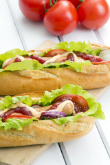 domowe hot dogi na białym drewnianym tle.