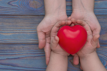 the hands of an adult and a child are held in the red heart, health insurance, family insurance,...