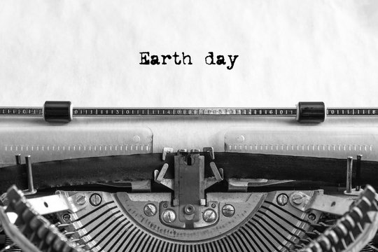 Earth day text is typed on a vintage typewriter with black ink on old paper, close-up