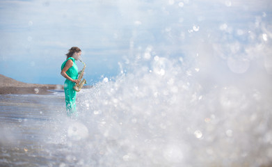 Person playing the saxophone sitting on the rocks in front of a beautiful sea