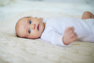 Baby girl lying on bed in nursery