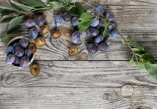 juicy ripe violet and yellow plums on dark kitchen table, rustic food photography on wooden background