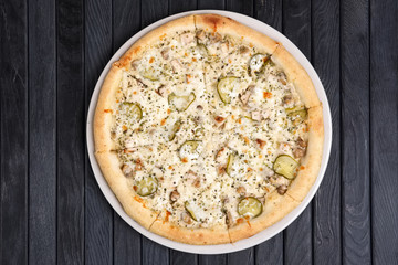 Top view of pizza with ham and slices of pickled cucumber