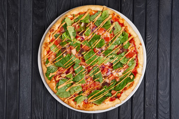 Top view of pizza with meat, pickled cucumber, onion, lettuce salad, tomato and barbecue sauce