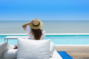 Woman tourist is taken vacation holiday and sitting at the pool on beach side in Thailand.