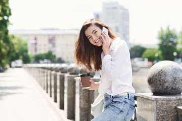 Happy girl talking on smartphone while standing outdoors