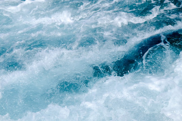 Troubled blue sea water with white foam, abstract nature background concept