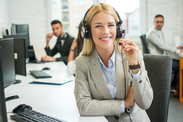 Cheerful young blonde customer service operator at call center