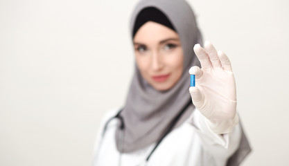 Naklejka premium Arab woman doctor in gloves holding pill