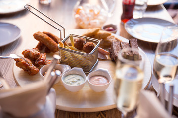 leisure, food, drinks, people and holidays concept - happy friends eating snack and drinking beer at bar or pub