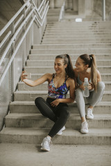 Two athlete women resting and taking selfie after jogging