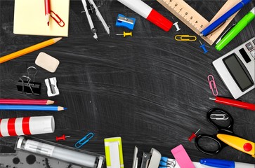 Colorful school supplies on blackboard background