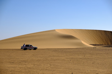 Car in sudanese desert in front of a dune - 1