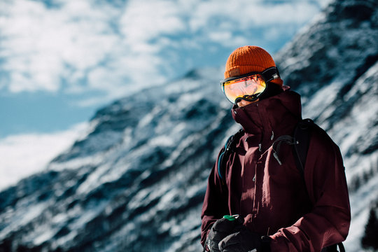 skiier with googles standing in alp environment with mountain all around him in sunny weather