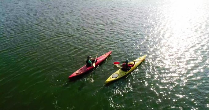 Two kayaks are sailing along a scenic river. Aerial view. Slow motion.