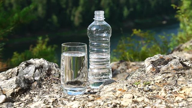 Bottle and glass of clean water on mountain area. Theme of health and ecology