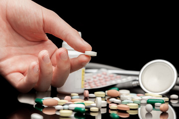 Pills in hand against black background