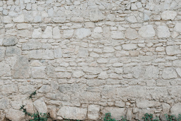 Gray stone wall with grass on the bottom. Stone texture. Stones with different shapes