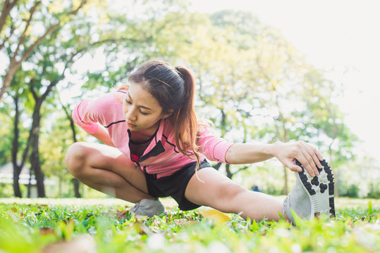 Healthy young asian woman exercising at park. Fit young woman doing training workout in morning. Young happy asian woman stretching at the park after a running workout. Exercise outdoor concept.
