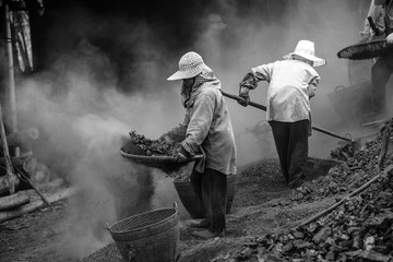 Workers are sorting charcoal at an ancient charcoal kiln.