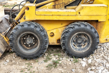 Close-up of a yellow mini excavator wheel on a construction site