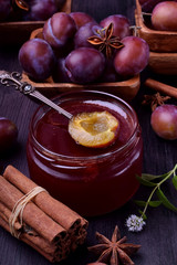 Plum jam in a glass jar surrounded by the berries