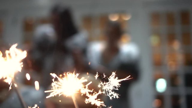 Holding sparklers outside at night as it snows, in slow motion