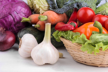 a variety of fresh vegetables including tomato pepper cabbage beetroot zucchini and carrot leaves garlic salad and cucumbers and garlic close-up on a white wooden and background