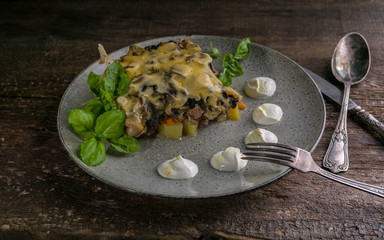 Julienne with mushrooms, cheese and herbs on a wooden background