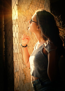 Woman leaning on the window with rusty metal fence