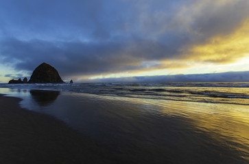 Fototapeta na wymiar Colorful sunset along the beach on Haystack Rock in Oregon