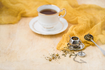 Elizabethan Bone China Tea Cup and Saucer with Herbal Tea and Tea Infuser on Yellow Background