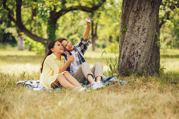 Two adorable kids taking self pictures. Young mr and miss taking selfis together while at picnic...