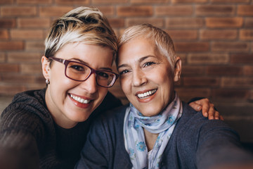 Senior mother sitting in cafe bar or restaurant with her middle age daughter, they are smiling and...