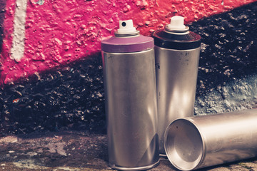 Several spray cans with paint and caps for spraying paint under pressure is lies near the painted...