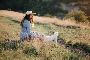 in autumn a girl in a hat is walking with a white dog