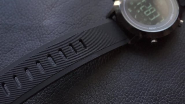black sport smart watch on black leather. slider effect horizontal panning slow motion close-up low key shot