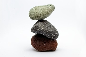 Pyramid of three colored stones over white background