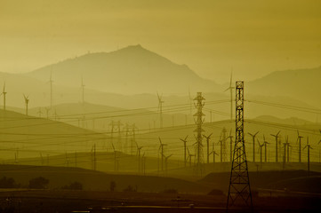 Wind Turbines and Electical Trasmission Towers partially obscured by dusty sky, Central Valley,...