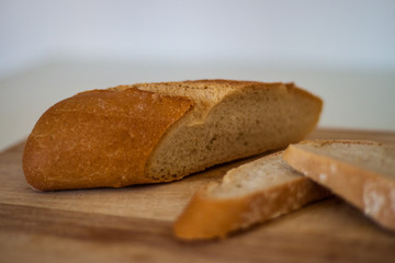 Fresh bread slice and cutting knife on rustic table