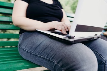 Fototapeta premium Sedentary work, stress, multitasking, online office. Young overweight female worker with laptop working outdoors